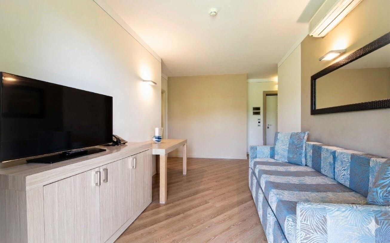 A modern living room with a flat-screen TV, a wooden cabinet, a small table, and a patterned sofa.