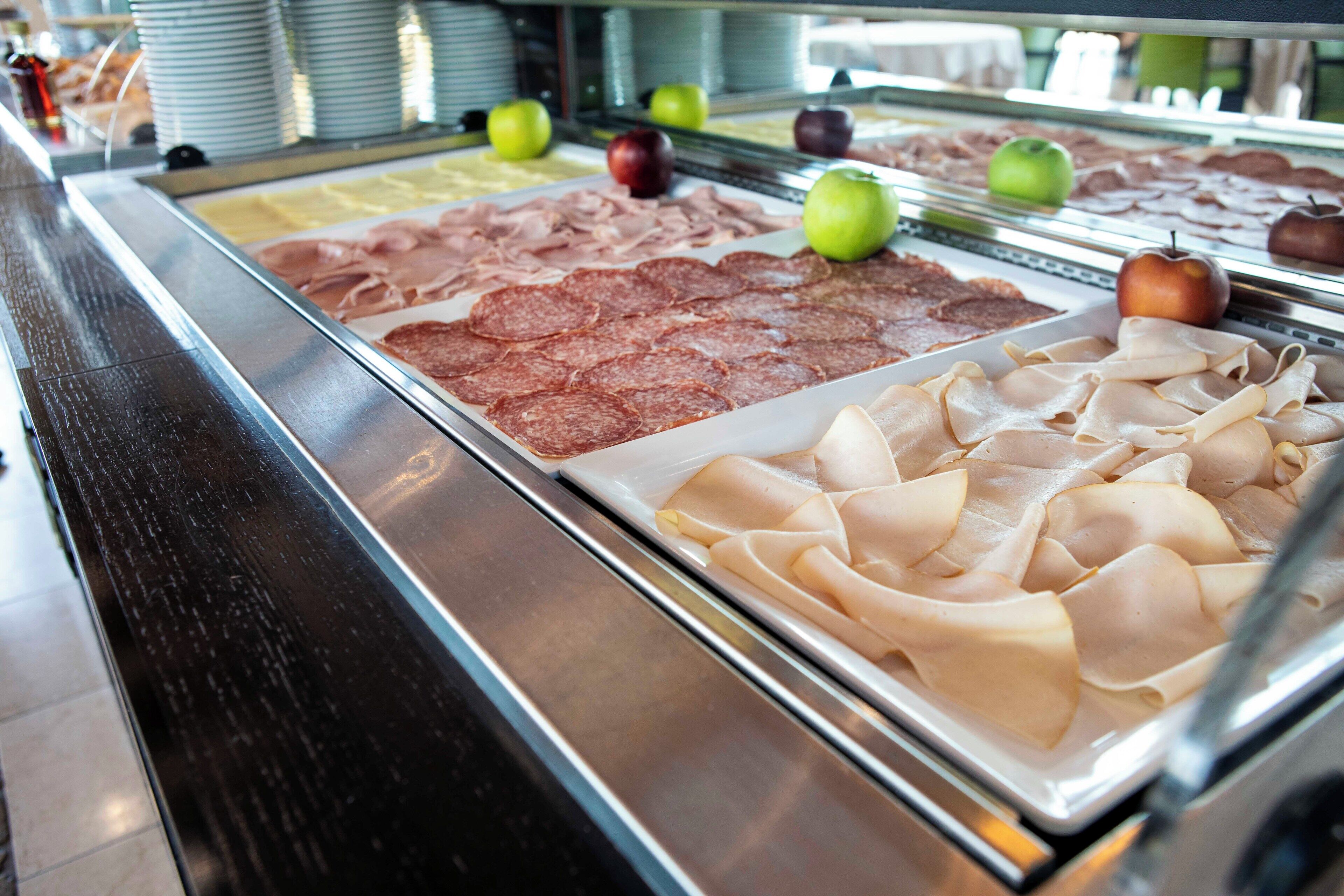 Un bufé con diversas opciones de comida, incluyendo embutidos y manzanas.