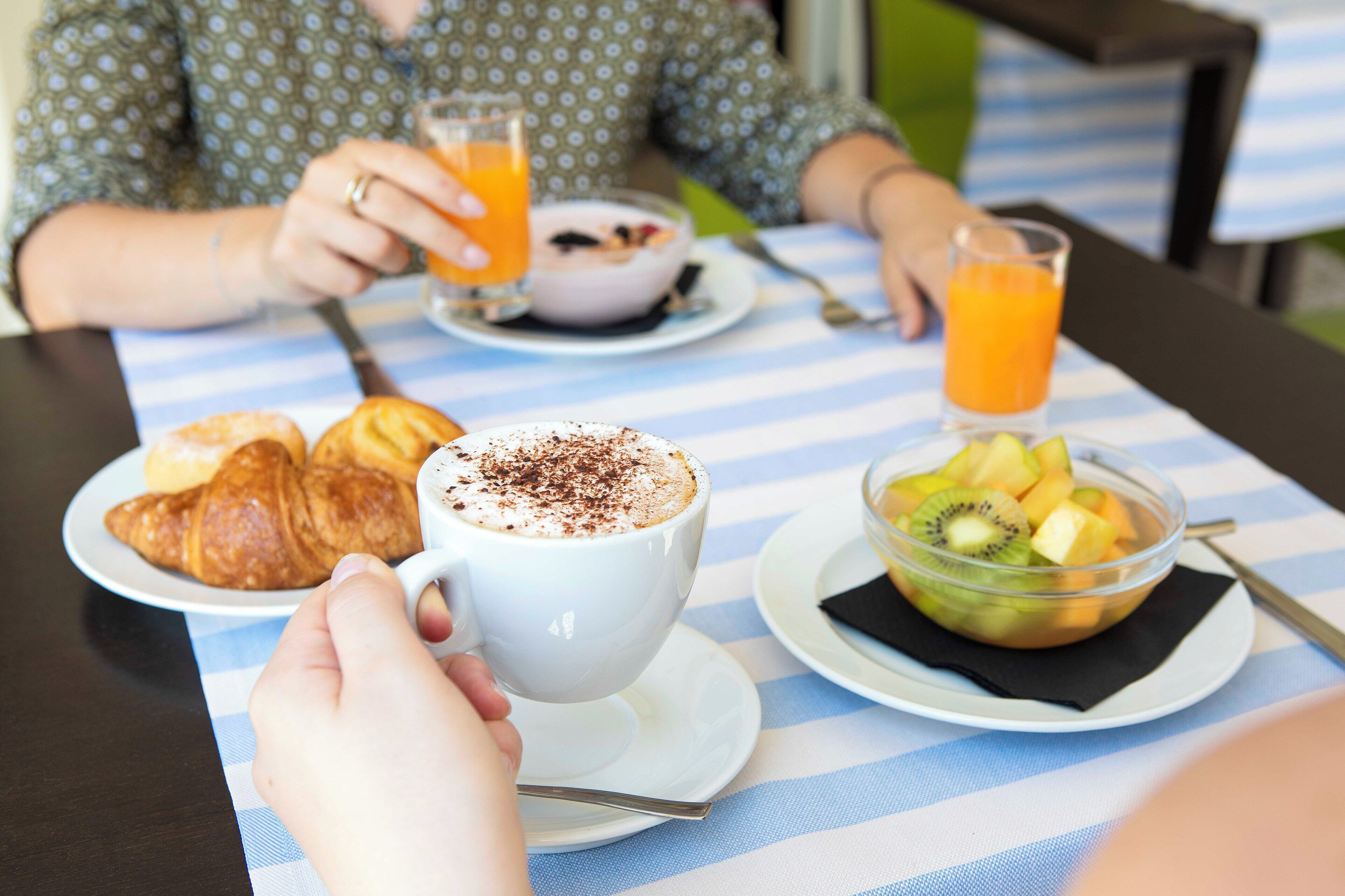 Ein Esstisch mit Tellern voller Essen, einer Kaffeetasse und einem Glas Orangensaft.