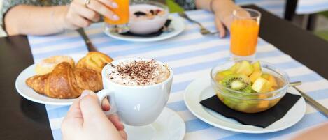Una mesa de comedor con platos de comida, una taza de café y un vaso de jugo de naranja.