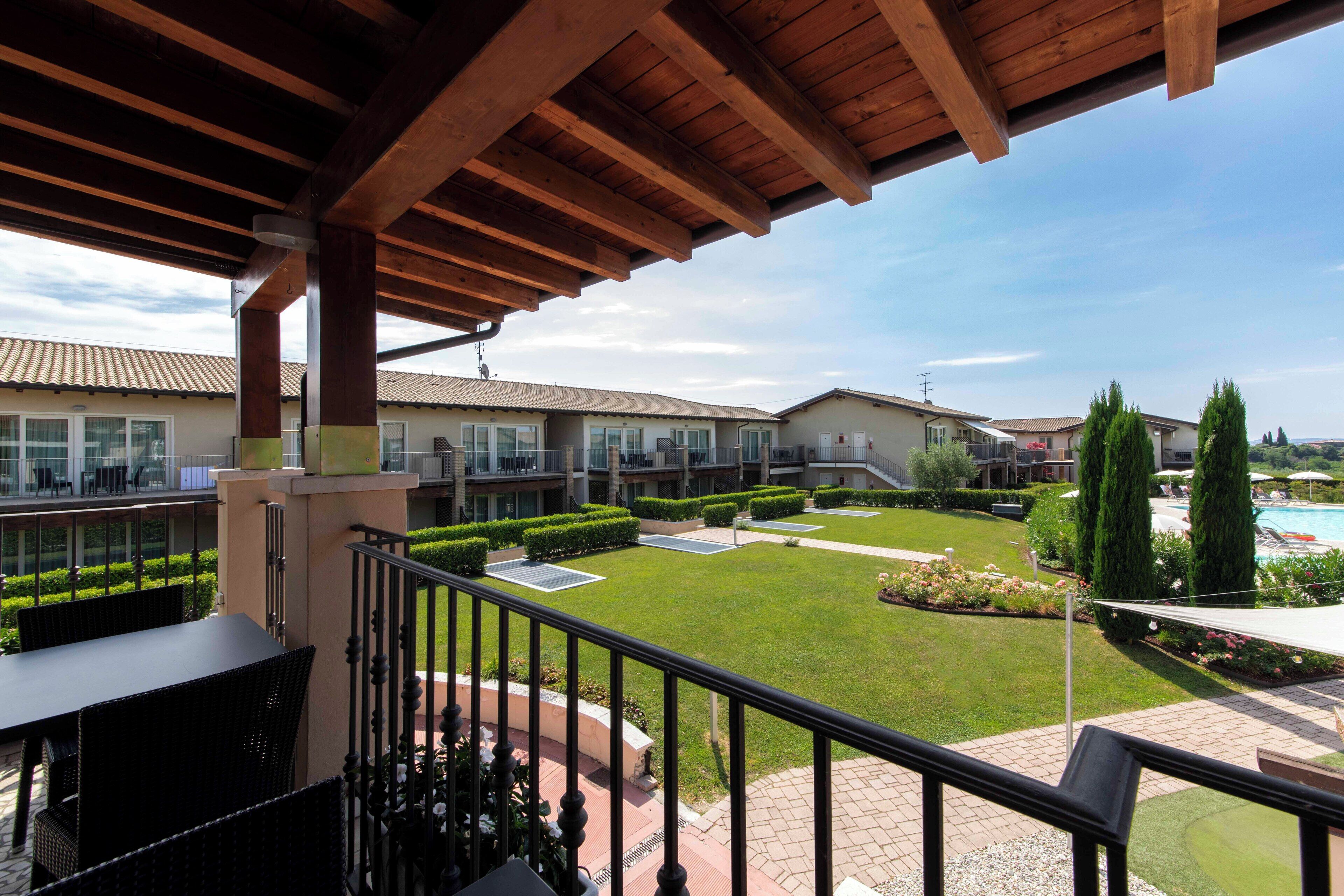A covered outdoor area with a patio, a pool, and a well-maintained lawn.