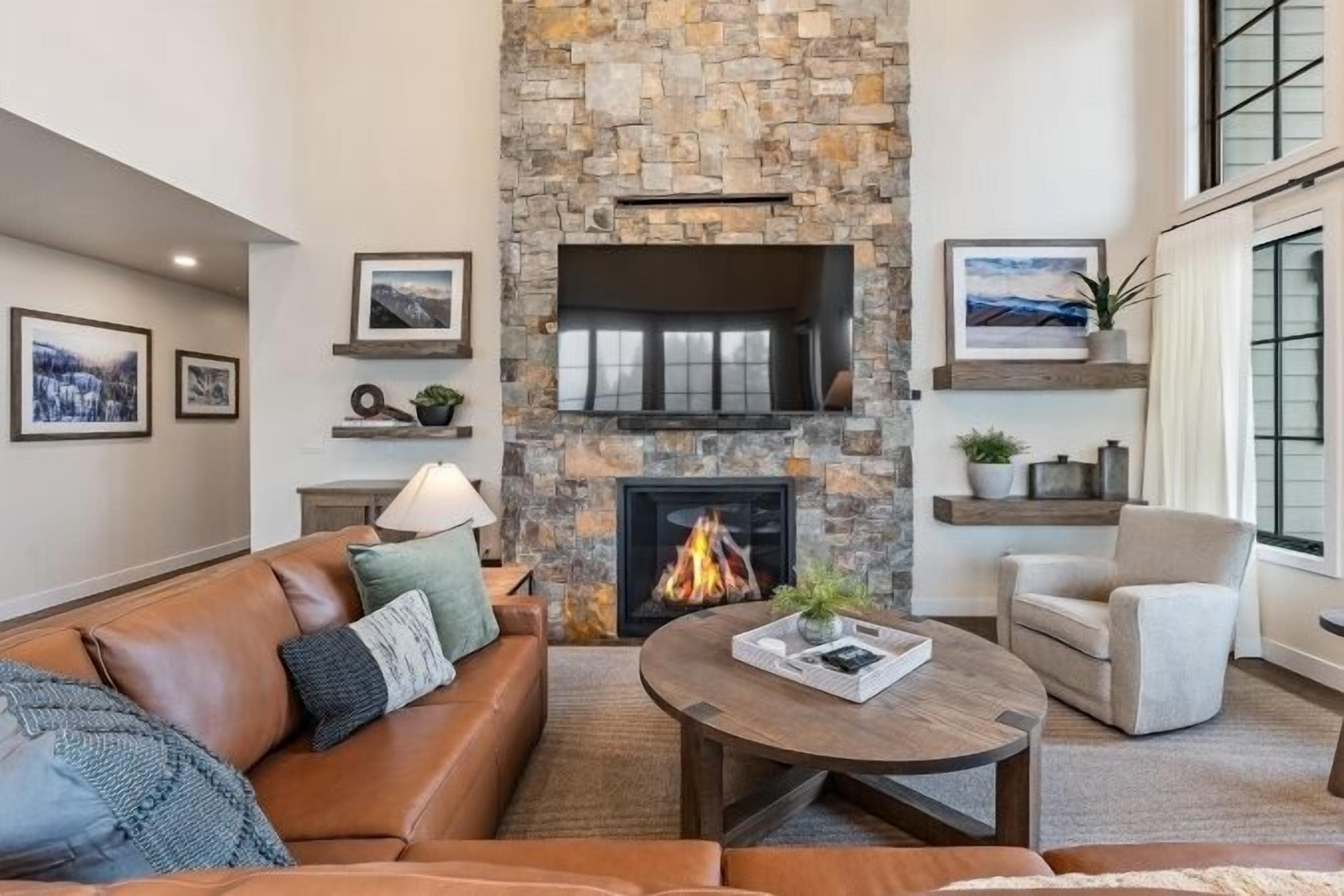 A cozy living room with a stone fireplace, leather sofa, and a coffee table.