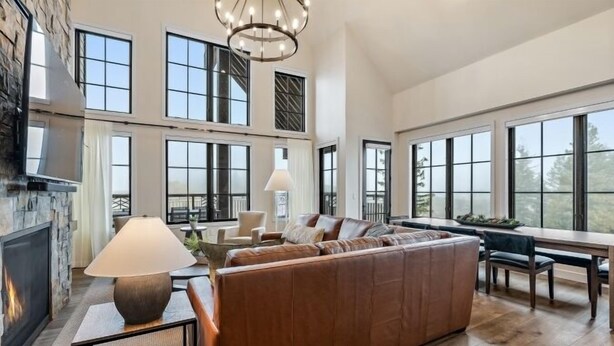 A spacious living area with a fireplace, large windows, and a high ceiling.
