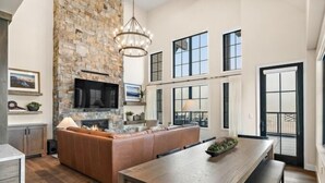 A spacious kitchen with a stone wall, a large island, and a dining area with a wooden table.