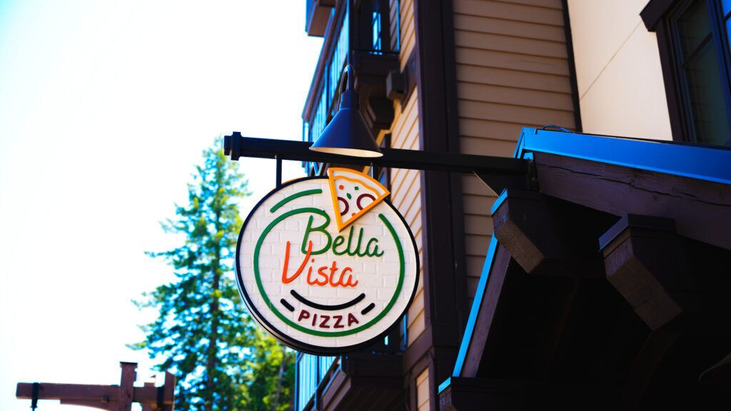 A pizza restaurant sign with the name "Bella Vista" and a pizza slice graphic.