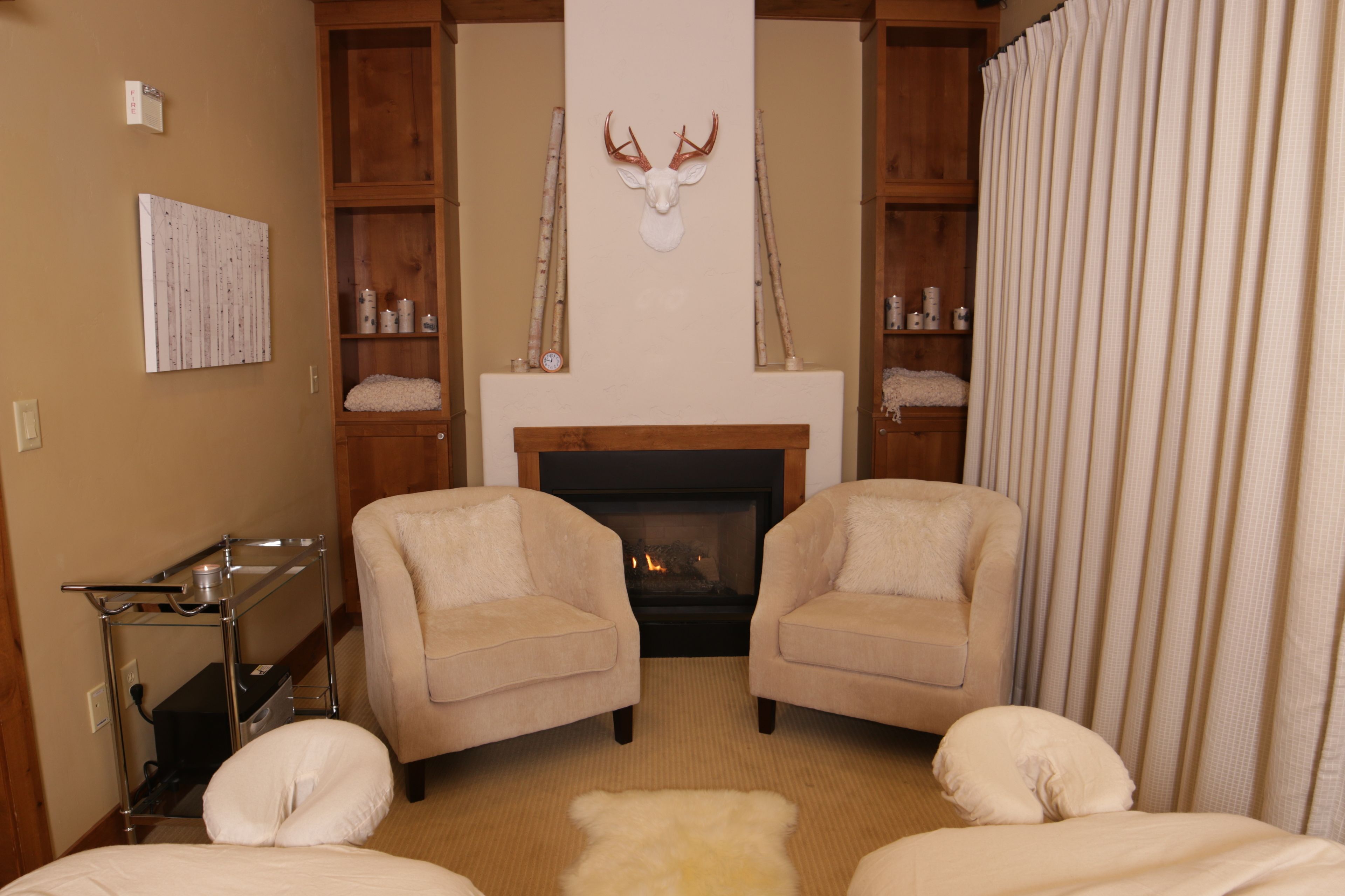 Una habitación acogedora con dos sillones, una chimenea y un armario de madera con estantes.