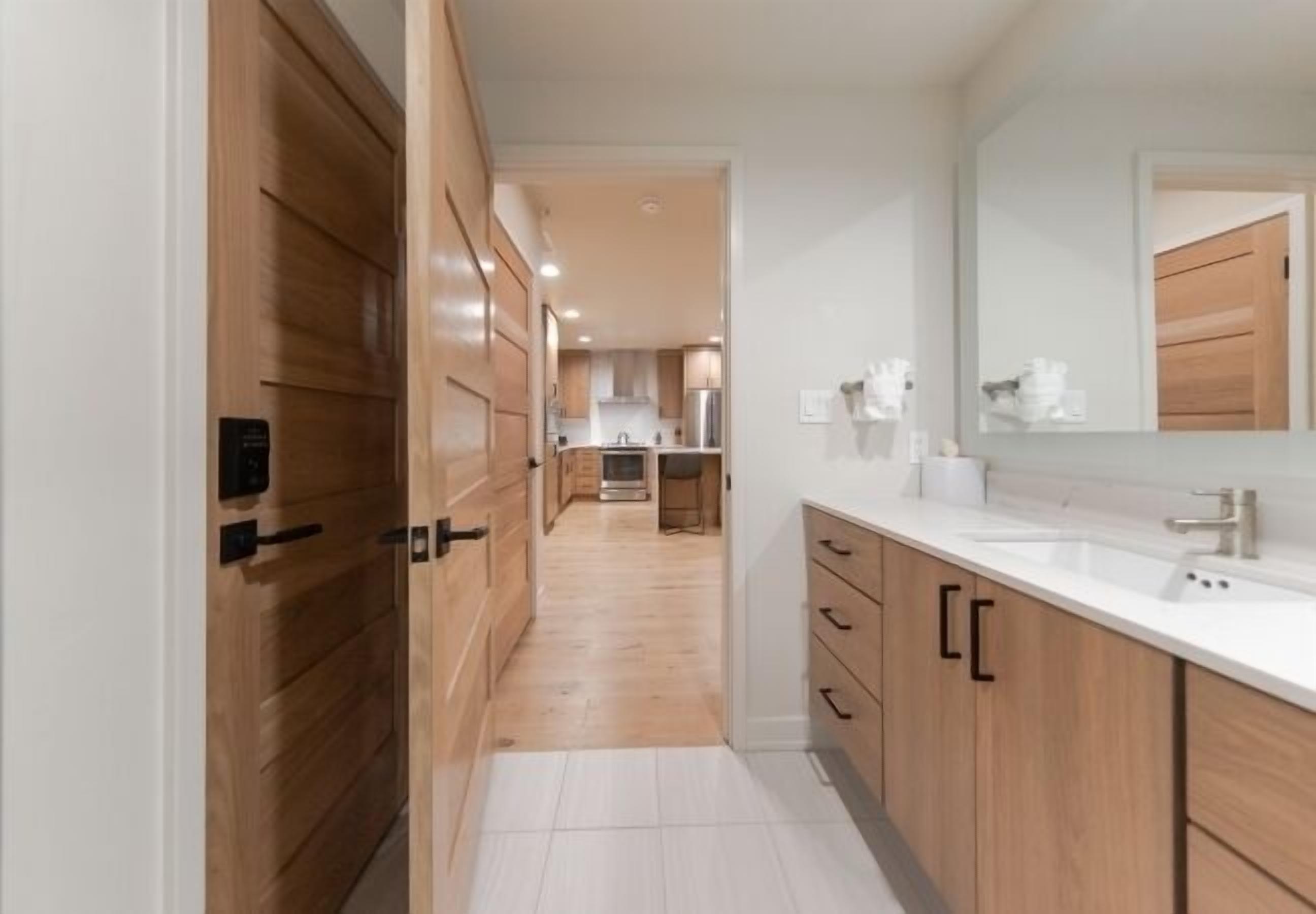 Una cocina moderna con armarios de madera, encimera blanca y un espejo grande.