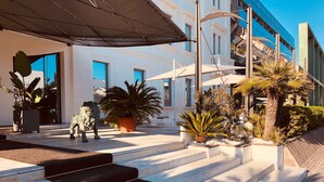 A modern building with a white facade, large windows, and a set of black carpeted stairs leading to a covered entrance. - Kursaal Hotel (Cattolica)