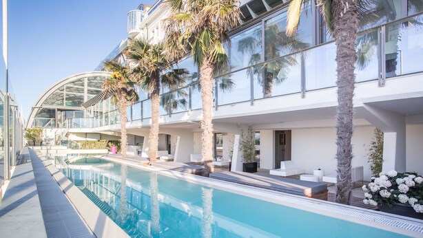 A modern hotel with a swimming pool, palm trees, and a glass conservatory. - Kursaal Hotel (Cattolica)