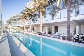 Un hotel moderno con piscina, palmeras y un invernadero de vidrio.