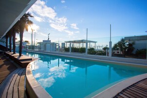 Una piscina al aire libre, sillones reclinables de piscina