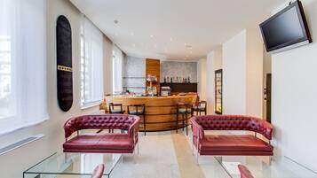 A modern interior with a bar area, leather sofas, and a flat-screen TV.