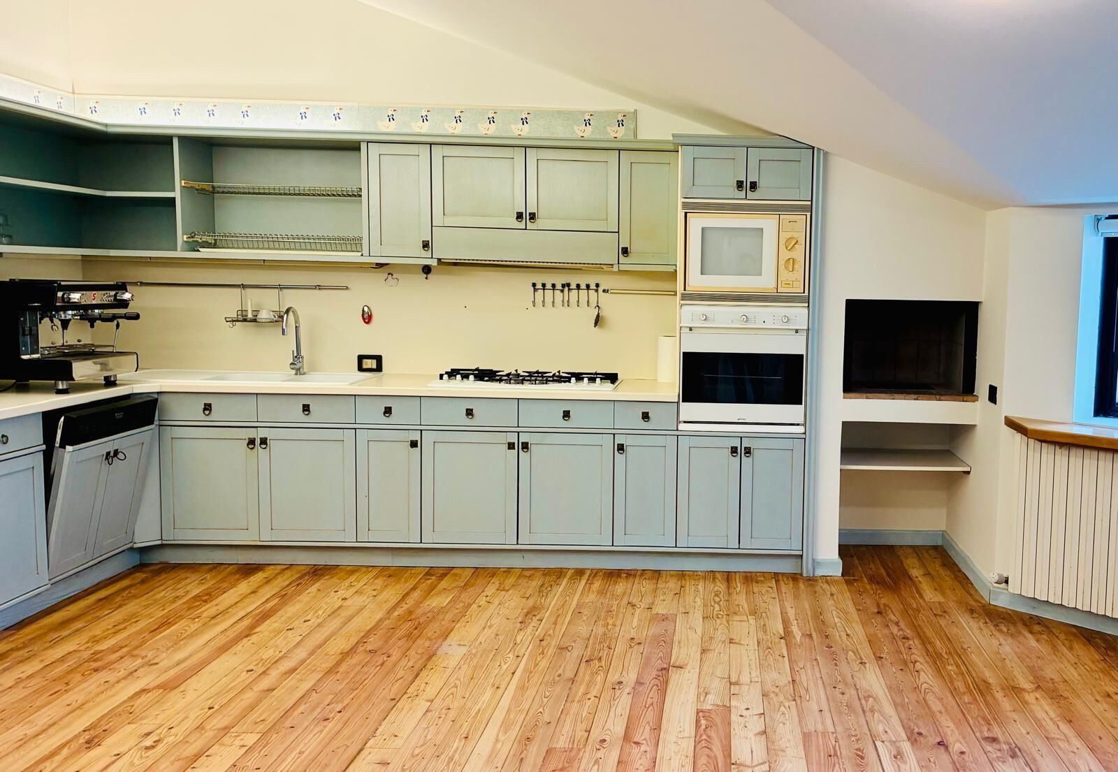 A kitchen with light blue cabinets, a gas stove, a microwave, and a dishwasher.