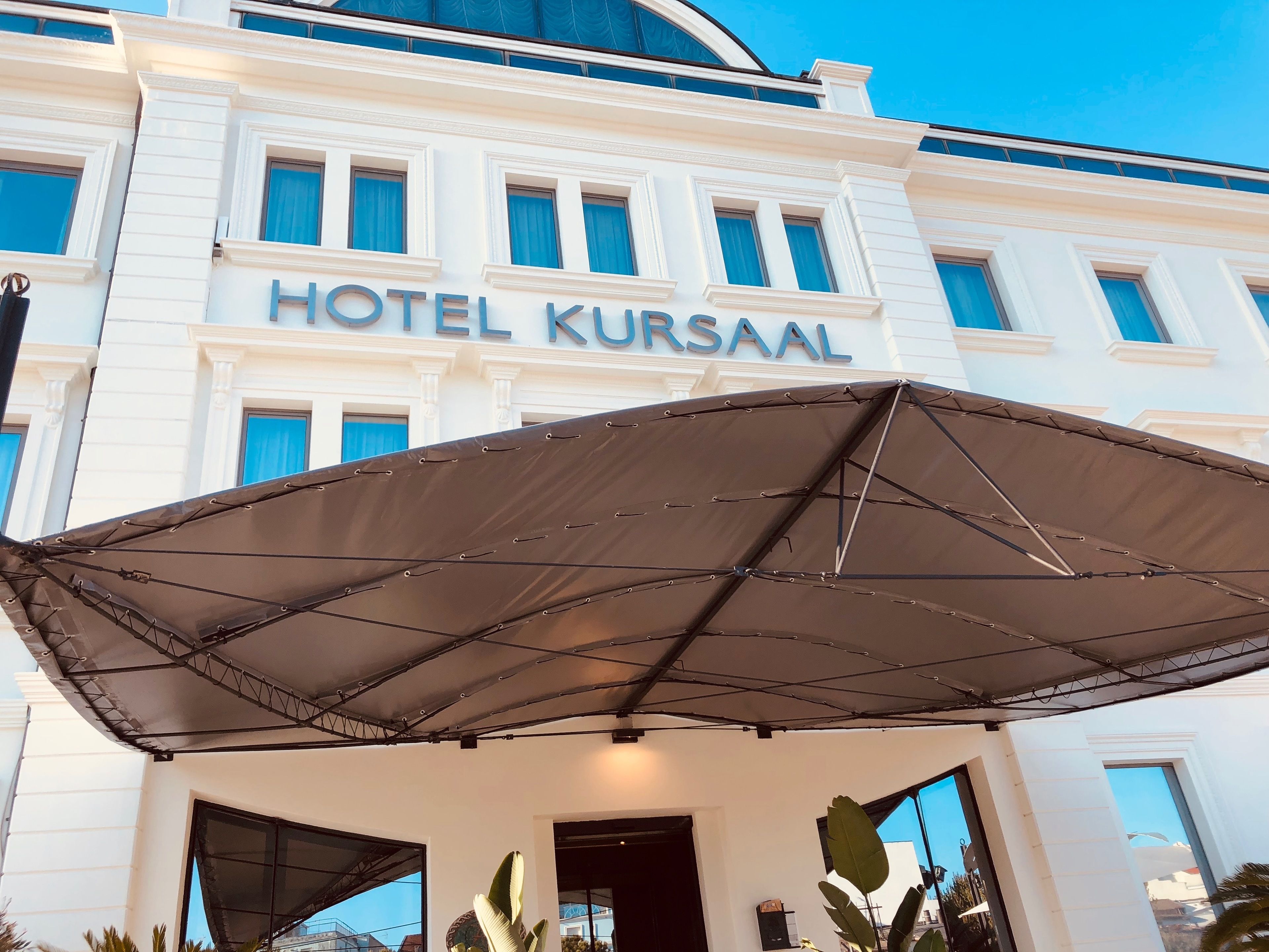 Un hotel llamado HOTEL KURSAAL con un amplio toldo sobre la entrada.