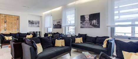 A modern hotel lobby with multiple black sofas, a coffee table, and large windows.