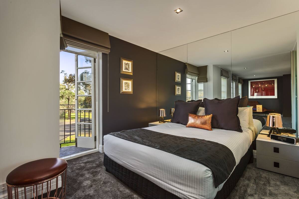Un dormitorio moderno con una cama grande, una zona de estar y vistas al exterior.