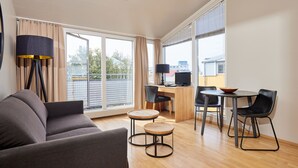 A modern living room with a sofa, a coffee table, and a dining area with a table and chairs. - Hotel Fron (Reykjavik)
