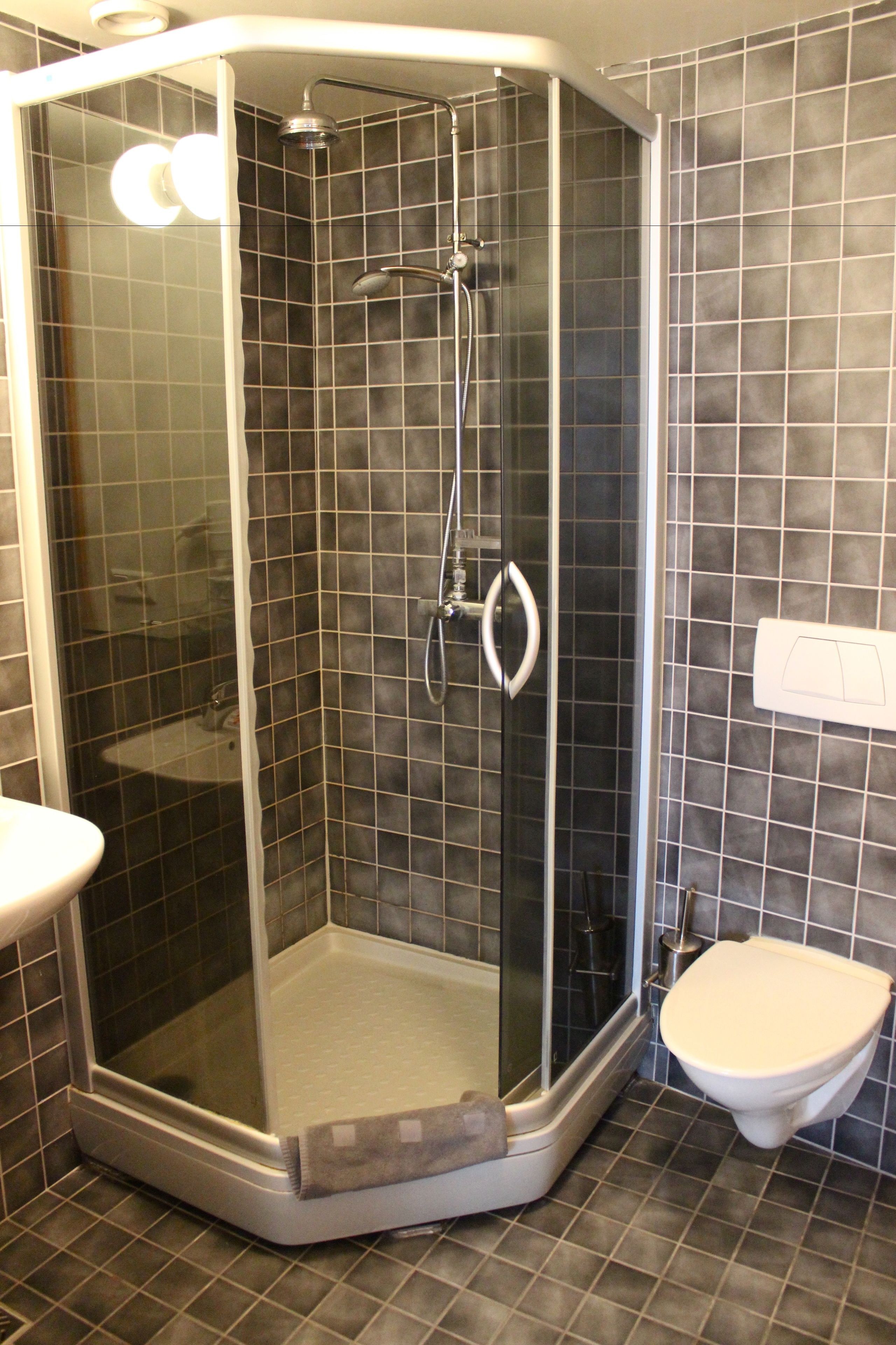 Une cabine de douche avec une porte en verre, un lavabo blanc et des toilettes.