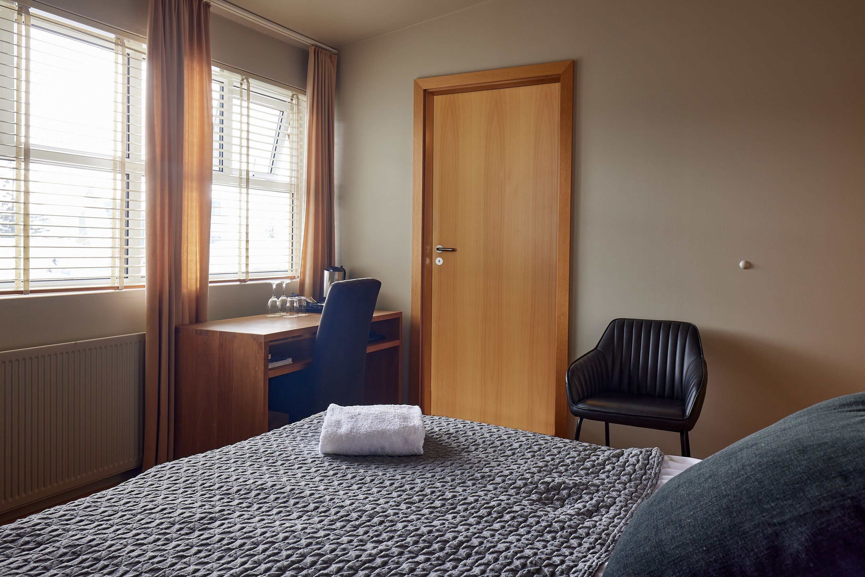 A bedroom with a bed, a desk, a chair, and a wardrobe.