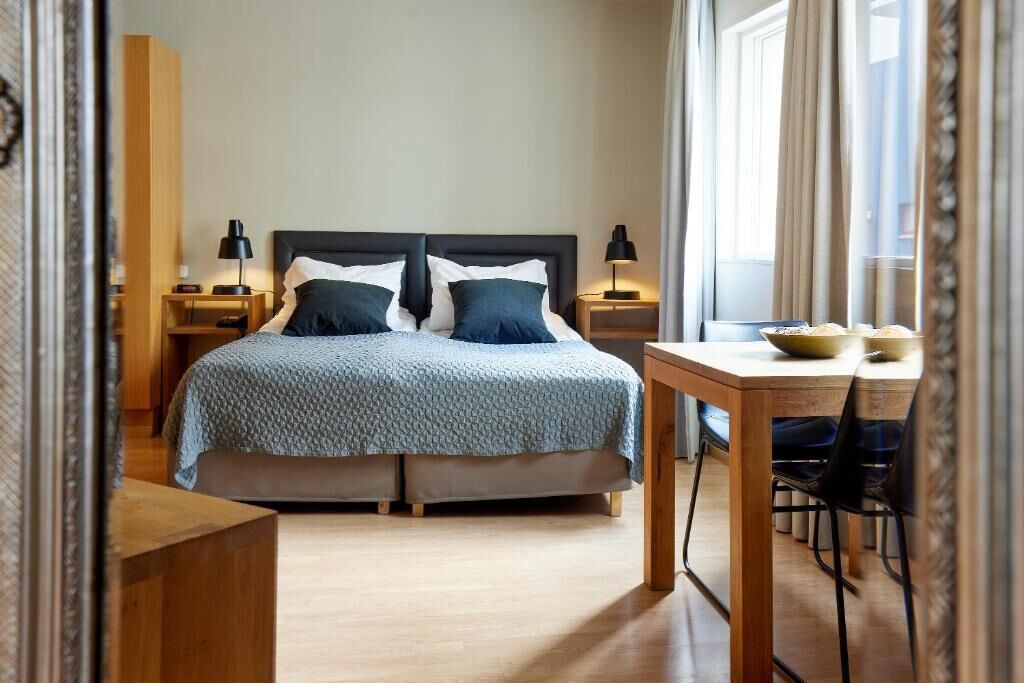 A bedroom with a bed, bedside tables, a desk, and chairs.