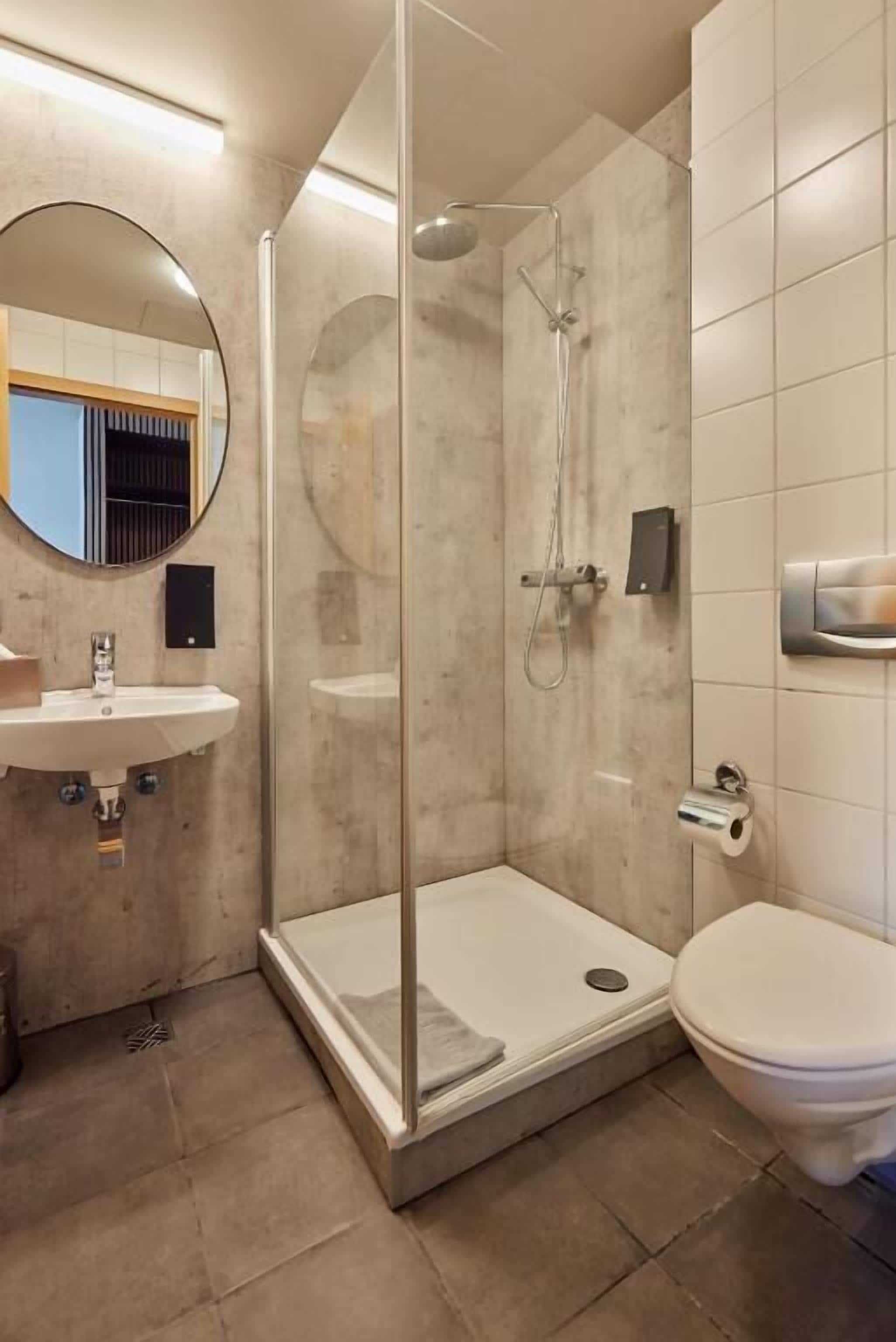 Un baño moderno con ducha de vidrio, lavamanos e inodoro.