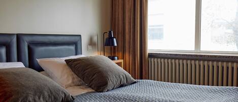 A neatly made bed with a patterned bedspread, two pillows, and a bedside lamp.