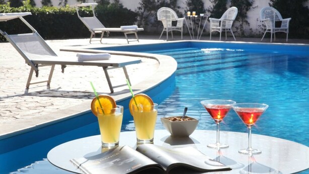 A poolside setting with lounge chairs, a table with drinks, and a magazine. - Ciampino Hotel (Ciampino)