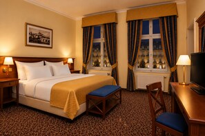 A hotel room with a bed, a desk, a chair, a television, and a window with curtains. - Hotel Louis Leger - Czech Leading Hotels (Prague)