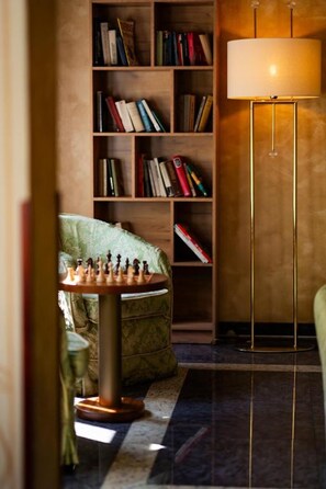 A cozy room with a chessboard, a bookshelf, and a floor lamp. - Hotel Louis Leger - Czech Leading Hotels (Prague)