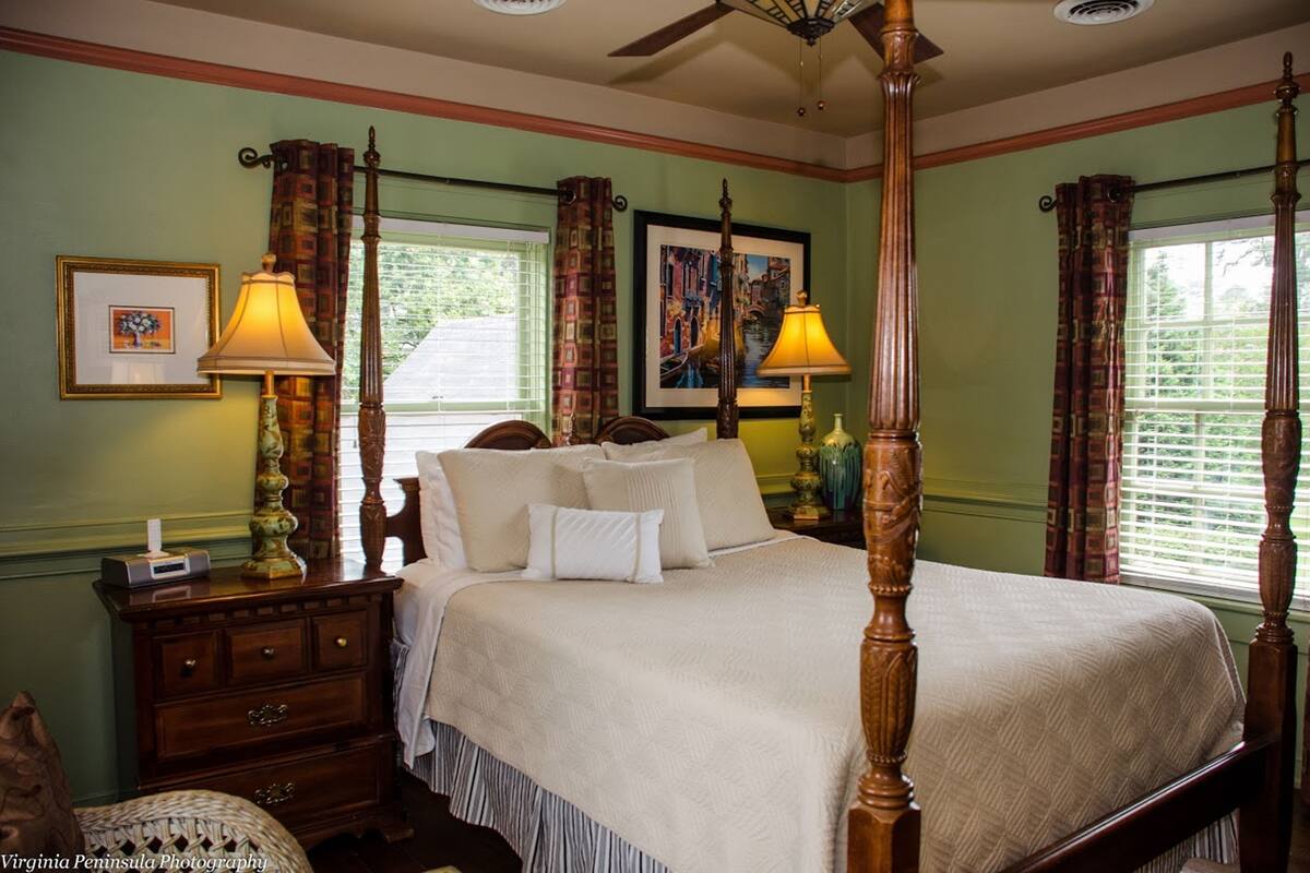 A four-poster bed with a wooden frame, a bedside table with a lamp, and a nightstand with a lamp.