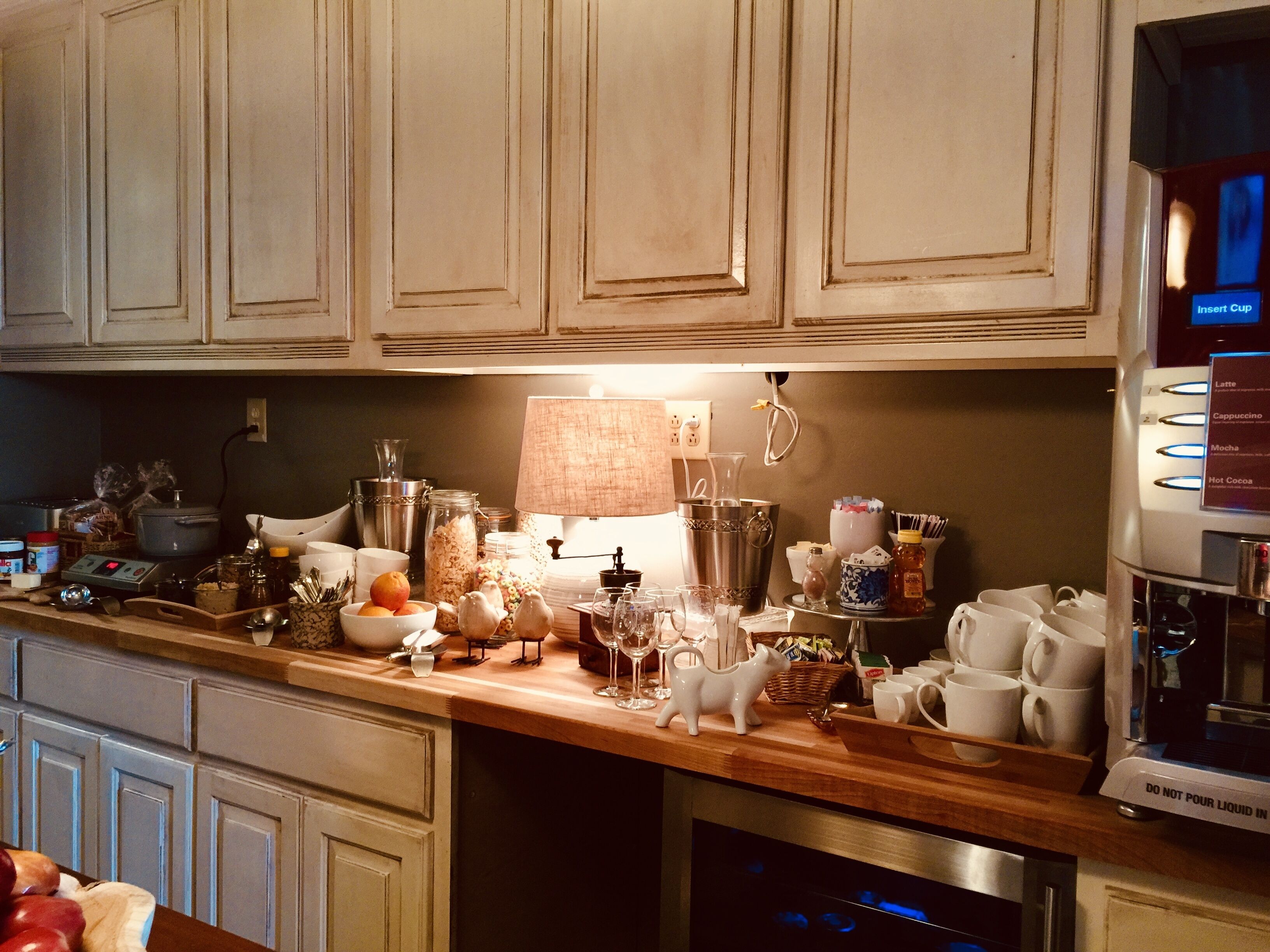 A kitchen counter with various items including a coffee machine, jars, a lamp, and kitchen utensils.