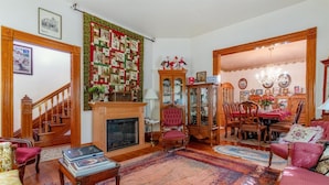 Un salon traditionnel avec une cheminée, un coin repas avec des meubles en bois et un escalier.