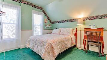A bedroom with a bed, a chair, a nightstand, a lamp, and a window.