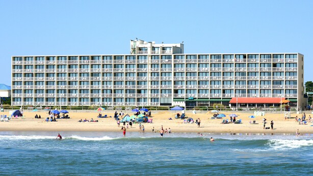 A large hotel with multiple balconies and a beach in front. - Oceanfront Inn (Virginia Beach)