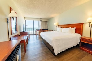 Ein Hotelzimmer mit einem großen Bett, einem Schreibtisch, einem Sessel und einem Balkon mit Blick.