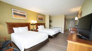 A hotel room with two beds, a TV, and a desk. - Oceanfront Inn (Virginia Beach)