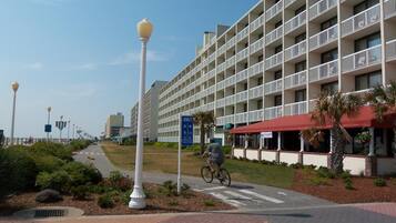 Un hotel frente al mar con varios balcones, una ciclovía y un paseo peatonal.
