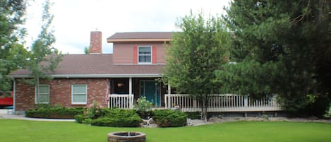 A two-story house with a front porch, a brick chimney, and a small front yard with a circular flower bed.