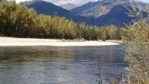 Un río con montañas al fondo y árboles a lo largo de la orilla.