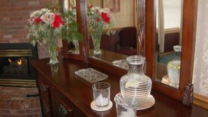 Un aparador de madera con espejo, una chimenea y elementos decorativos como jarrones y un decantador de cristal.