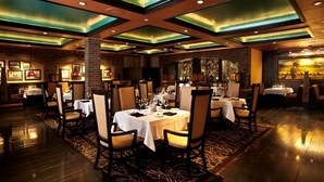 A restaurant with tables set for dining, featuring a brick wall and a large window with a view. - Carson Valley Inn (Minden)