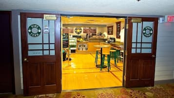 Interior de un restaurante con suelo de madera, taburetes verdes y una barra.