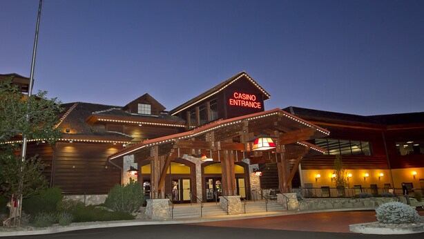 A building with a 'CASINO ENTRANCE' sign, wooden exterior, and a flagpole with an American flag. - Carson Valley Inn (Minden)