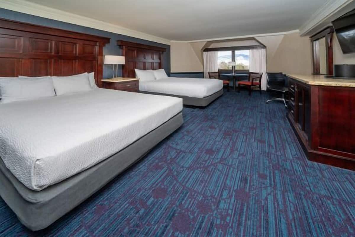 Une chambre d’hôtel avec deux lits, un bureau et une chaise.