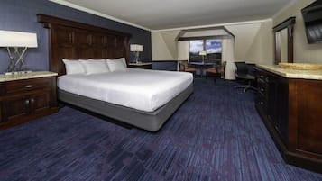 A hotel room with a large bed, a desk, and a view of the outdoors.