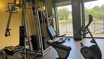 A gym with exercise equipment, a bench, and a window with a view of a park.