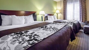 Quarto de hotel com duas camas, paredes verdes e uma grande janela com cortinas.