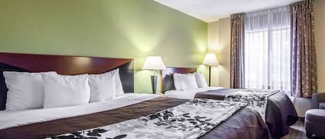 Habitación de hotel con dos camas, paredes verdes y un ventanal con cortinas.