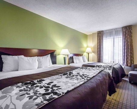 A hotel room with two beds, green walls, and a large window with curtains.