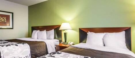 A hotel room with two beds, each with a wooden headboard, a nightstand with a lamp, and a framed picture on the wall.